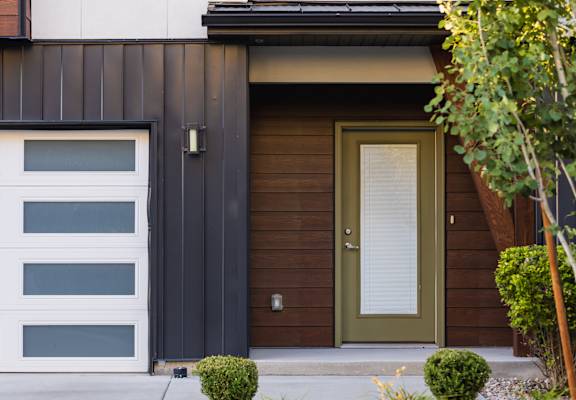 A modern house with a white garage door and a green door.