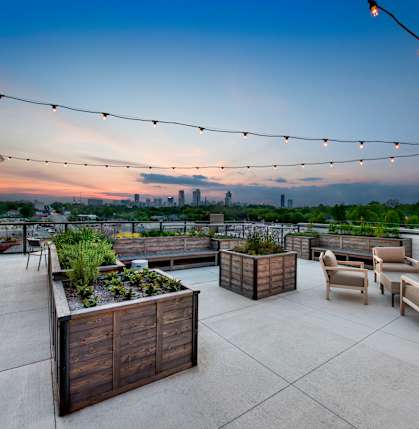 A rooftop patio with wooden furniture and string lights.