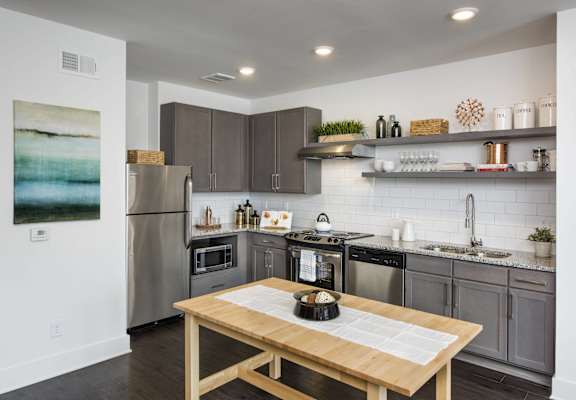 A modern kitchen with a wooden table and stainless steel appliances.