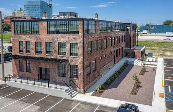 A red brick building with a parking lot in front.