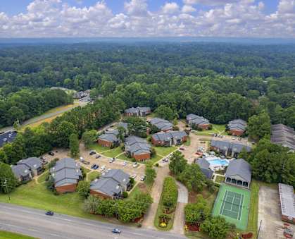 A bird's eye view of a residential area with houses, a tennis court, and a road.