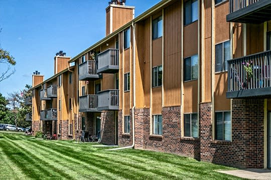 a brick building with balconies and a green lawn