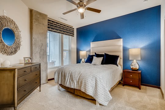 A bedroom with a bed, dresser, and ceiling fan. at Waterford RiNo Apartments, Colorado