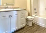 Thumbnail 18 of 27 - A white bathroom with a toilet, sink, and bathtub.