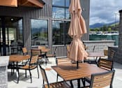 Thumbnail 8 of 27 - A patio with wooden chairs and tables with a view of the mountains.