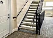 Thumbnail 11 of 27 - A staircase with a black railing and a white door with the number 201 on it.