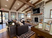 Thumbnail 6 of 27 - A modern living room with a stone fireplace and a pool table.