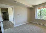 Thumbnail 15 of 27 - A room with a carpeted floor and a window with a view of trees outside.