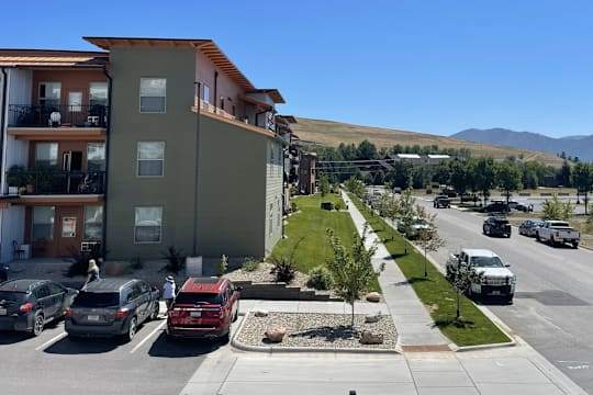 A sunny day in a residential area with cars parked on the street and apartment buildings.