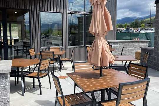 A patio with wooden chairs and tables with a view of the mountains.