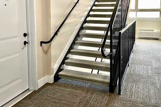 A staircase with a black railing and a white door with the number 201 on it.