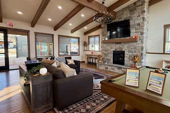 A modern living room with a stone fireplace and a pool table.