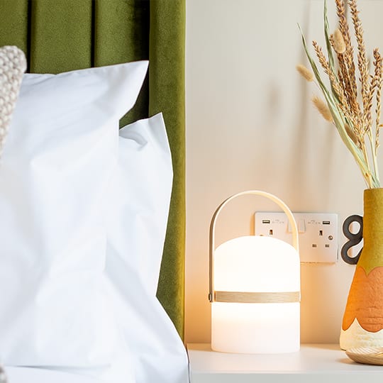a white nightstand with a white bag and a white pillow and a vase
