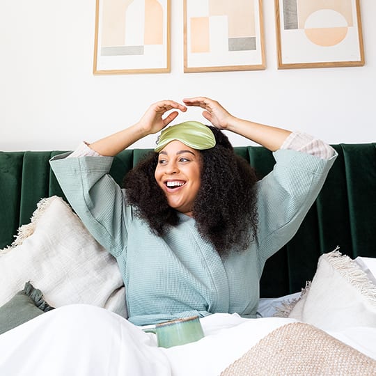 a woman laying in bed with a green towel on her head