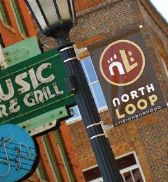 A sign for a music venue is hanging from a pole.