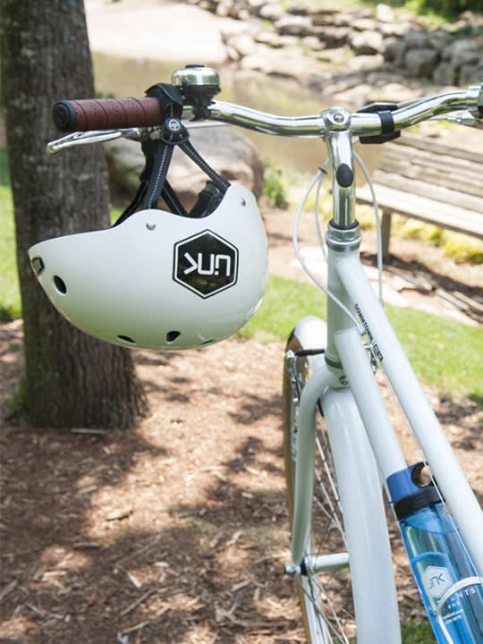 A Helmet Hangs from the Handlebars of a White Bike at Link Apartments 4th Street in North Carolina, 27101