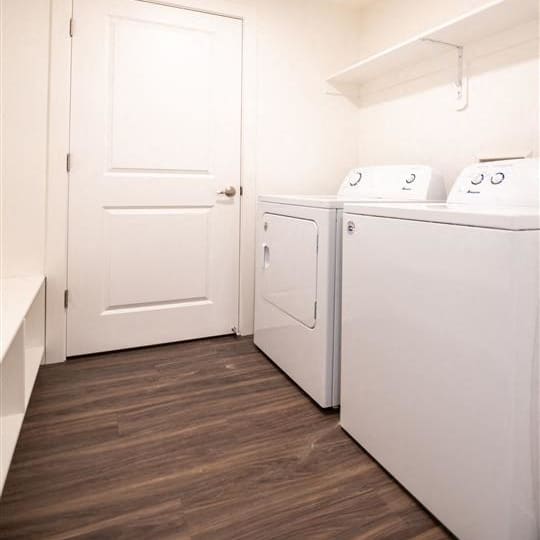 a white laundry room with two washes and a dryer