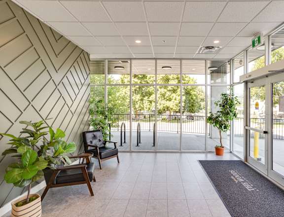 A hallway with a bench, potted plants, and a door.