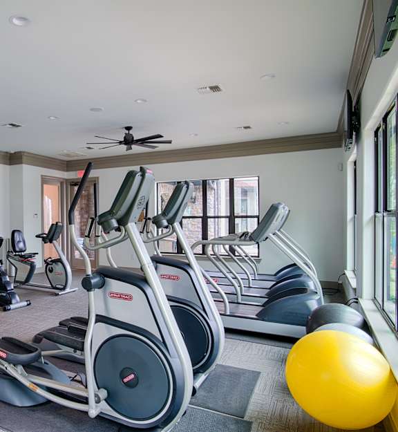 A gym with a variety of exercise equipment including treadmills, stationary bikes, and weight machines.