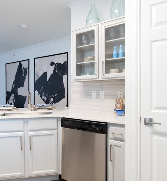 A kitchen with white cabinets and a black dishwasher.