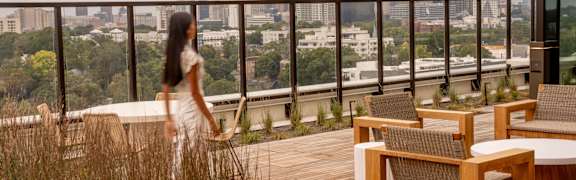 A woman walks on a wooden deck overlooking a city skyline. at Scout Living, powered by Placemakr Apartments, Atlanta, GA, 30308