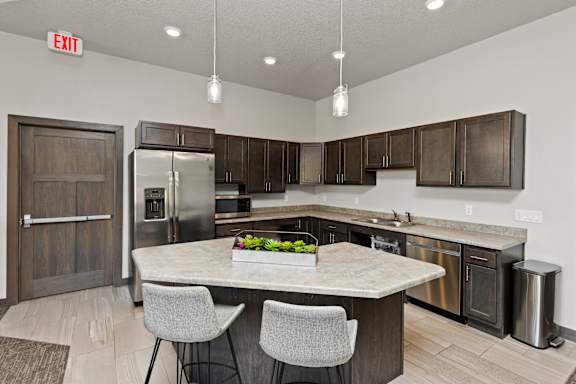 A kitchen with a marble table and grey chairs.