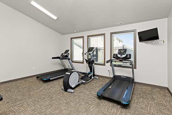 A room with a treadmill, elliptical trainer and a stationary bike.