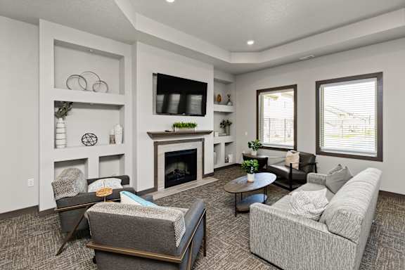 A living room with a grey couch, a fireplace, and a television.
