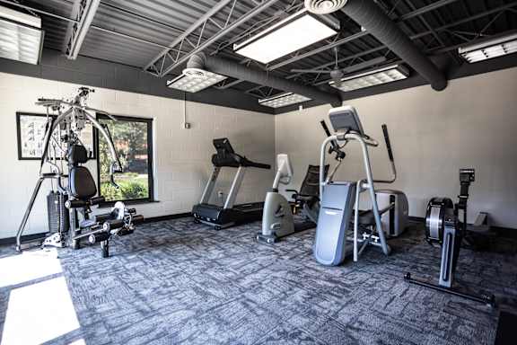 A gym with a variety of exercise equipment including treadmills, stationary bikes, and elliptical machines.