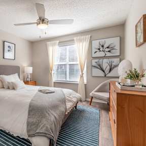 A bedroom with a bed, nightstand, and a ceiling fan.