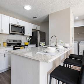 A kitchen with a white countertop and black chairs.