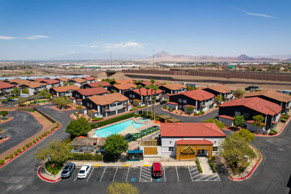 an aerial view of a community of homes with a pool and mountains in the background