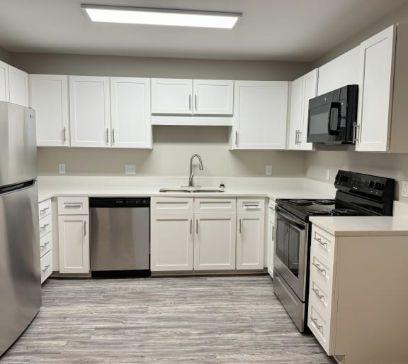 a kitchen with white cabinets and stainless steel appliances
