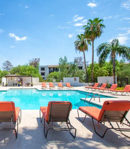 A pool surrounded by orange chairs.