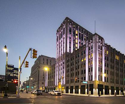 a tall building with purple lights at night on a city street at The Press/321, Detroit MI