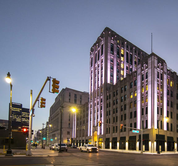 a tall building with purple lights at night on a city street at The Press/321, Detroit MI