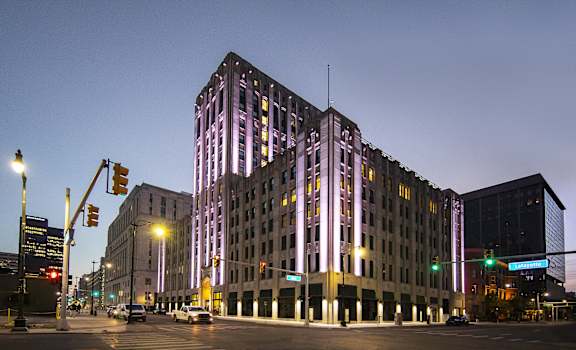 a tall building with purple lights at night on a city street at The Press/321, Detroit MI