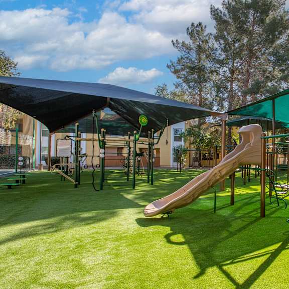 A playground with a green slide and a black canopy.