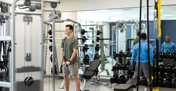 A man in a green shirt and shorts stands in a gym.