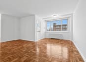Thumbnail 26 of 59 - A room with wooden flooring and a window overlooking a building.