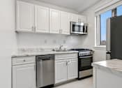Thumbnail 44 of 59 - A kitchen with white cabinets and appliances.