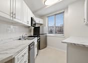 Thumbnail 17 of 59 - A kitchen with white cabinets, stainless steel appliances, and a marble countertop.