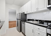 Thumbnail 30 of 59 - One bedroom kitchen with white cabinets, stainless steel appliances, and black countertops.
