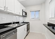 Thumbnail 31 of 59 - A kitchen with white cabinets and black countertops.