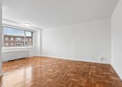 Thumbnail 27 of 59 - A room with wooden flooring and a window overlooking a building.