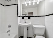 Thumbnail 49 of 59 - A white bathroom with a sink, toilet, and bathtub.