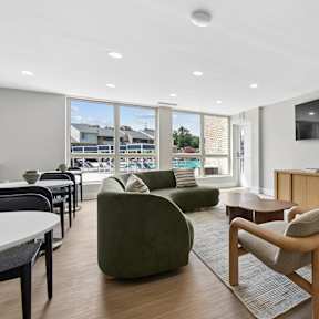 A living room with a green chair and a television on the wall.