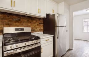 a kitchen with white cabinets and a brick wall