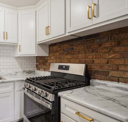 a kitchen with white cabinets and a brick wall