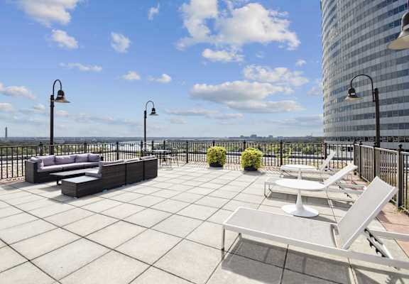 A patio with a couch, chairs, and a table with a view of the water.